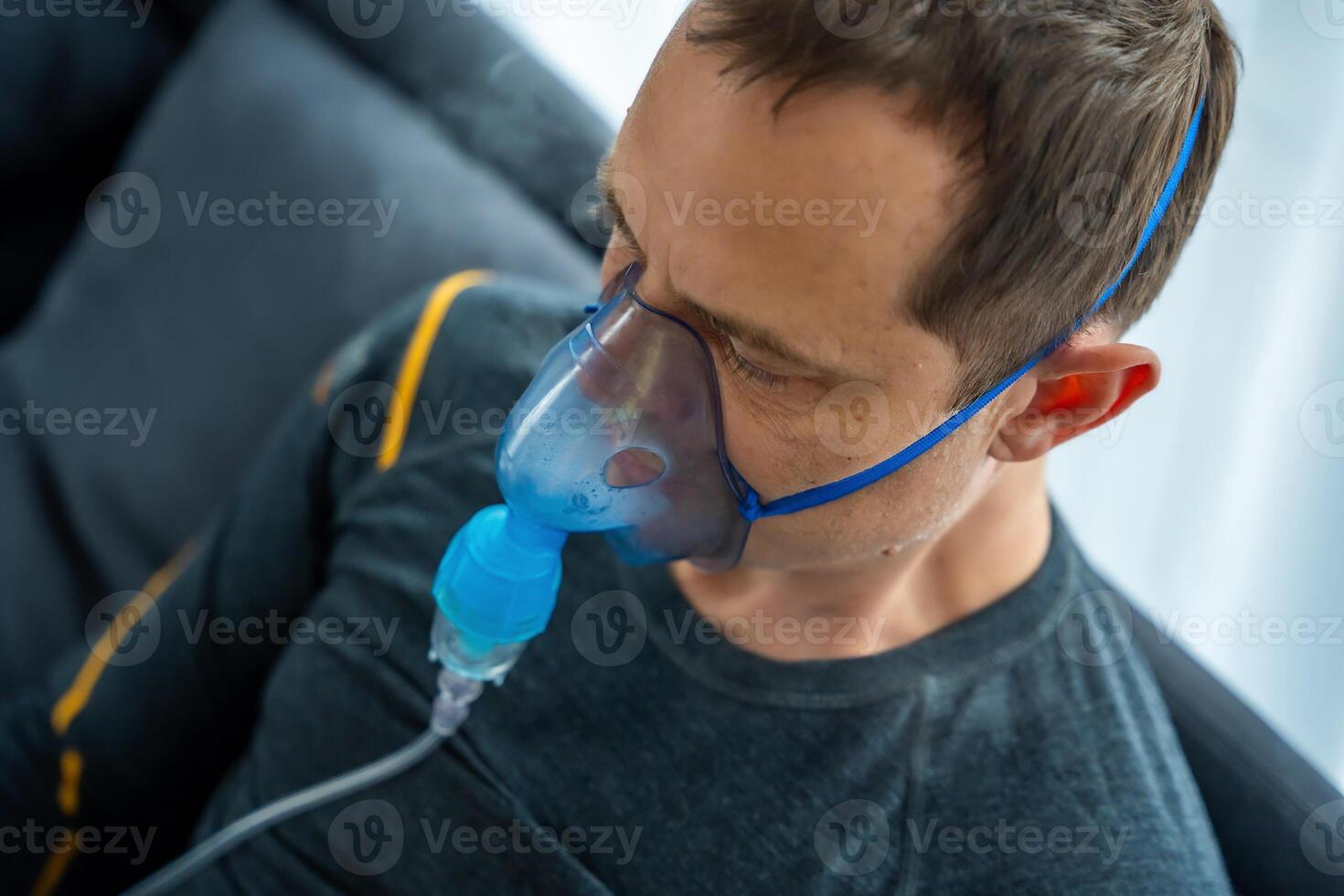 Unhealthy man wearing nebulizer mask in home. Health, medical equipment and people concept. High quality photo