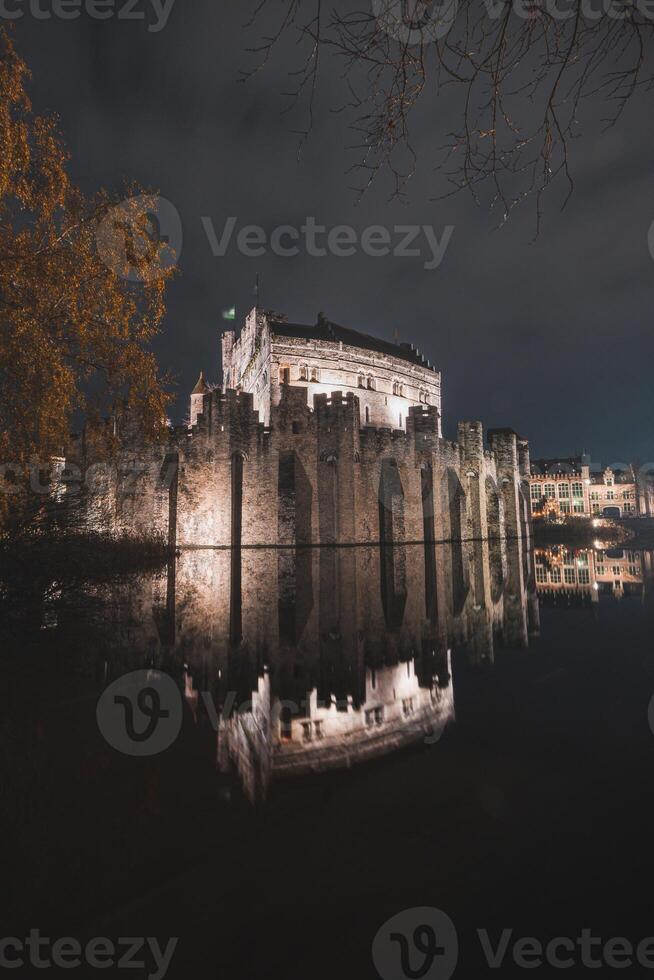 noche retrato de el medieval tumbado castillo en el centrar de gante, Bélgica. el reflexión de el paredes es en el agua canal foto
