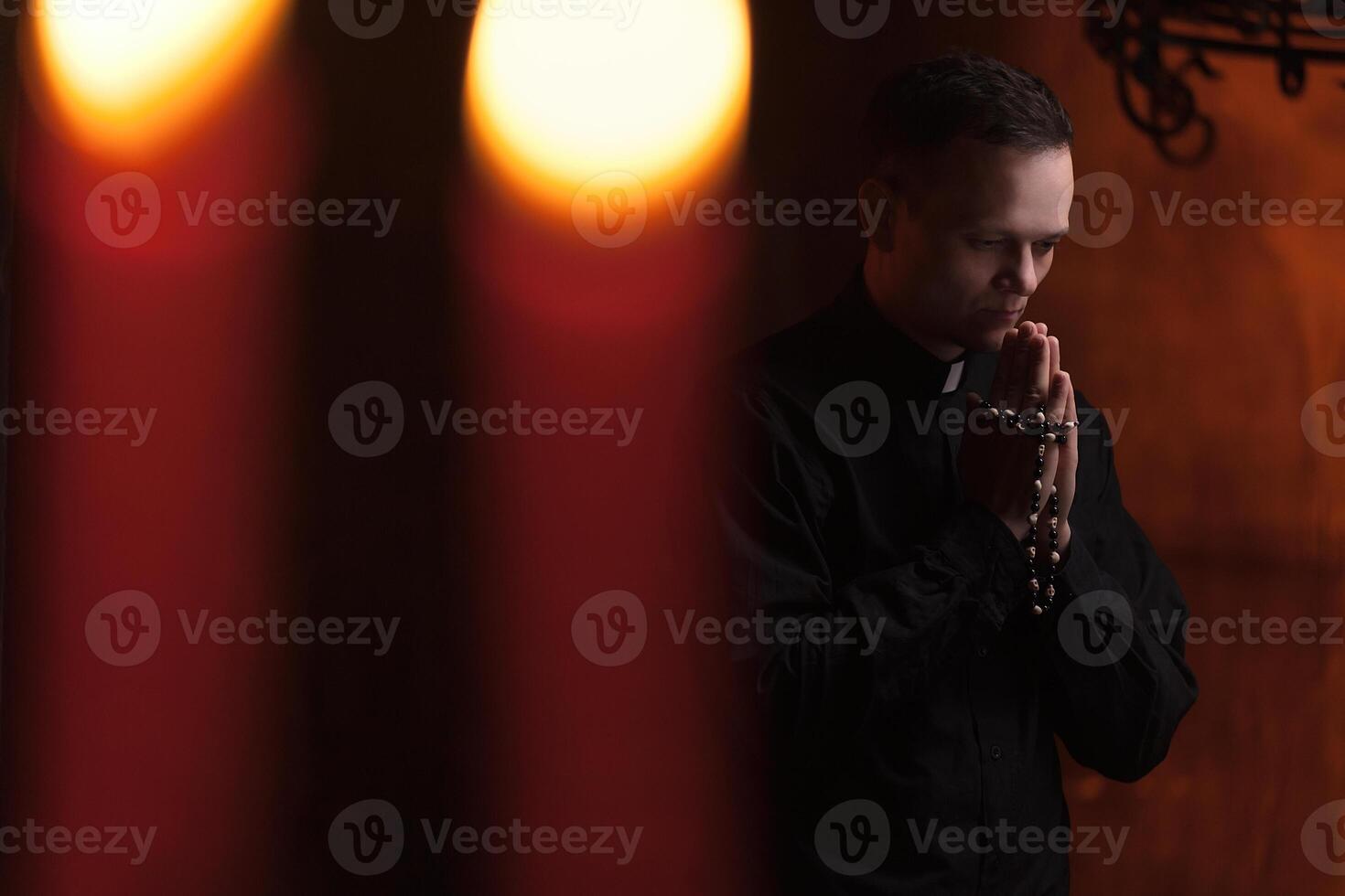 Praying priest. Portrait of priest Next to the candles prays photo