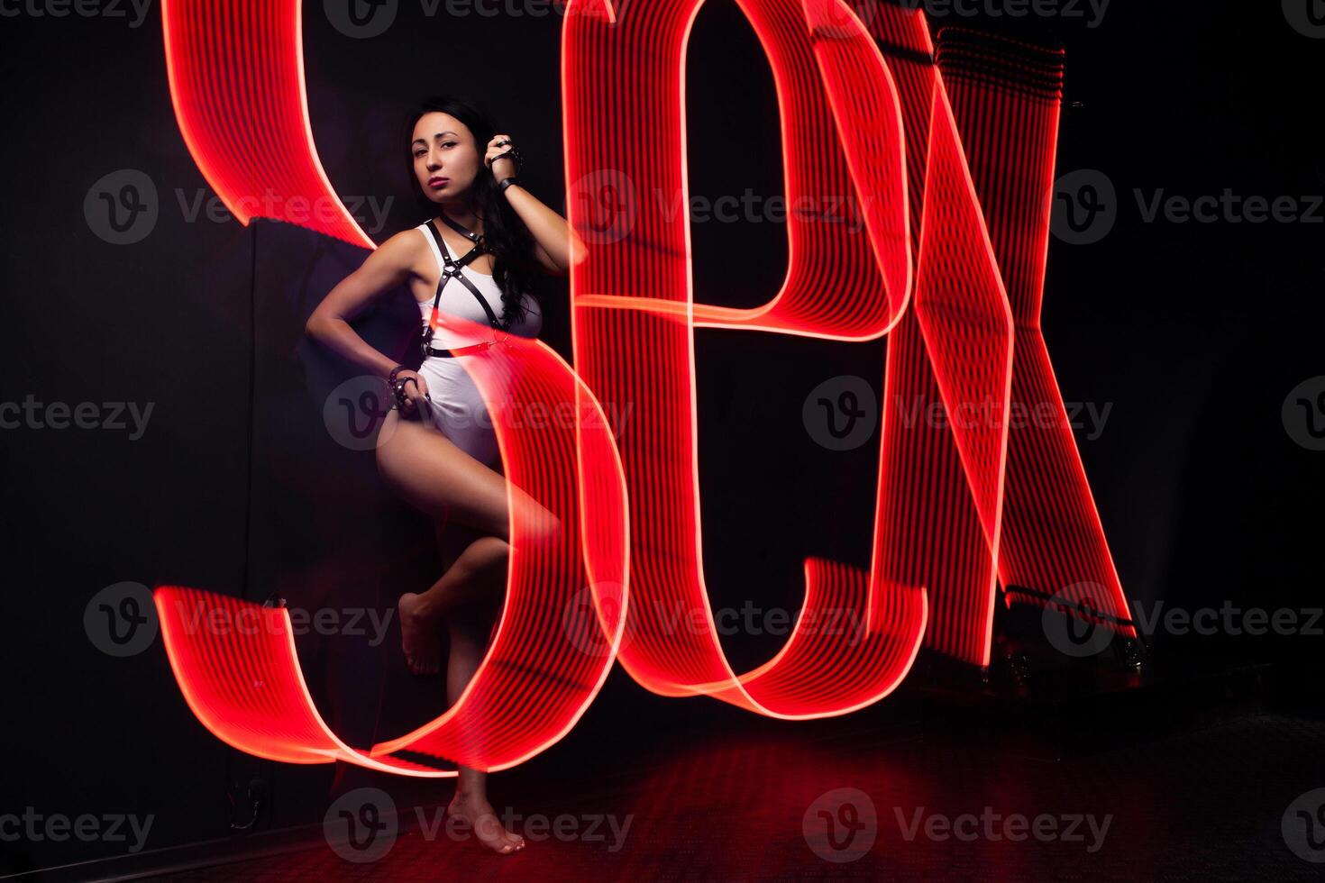 Hot sexy girl neon light dance night club concept dressed white night-club. Perfect female body with neon lettering on the background. Seductive female indoor photo