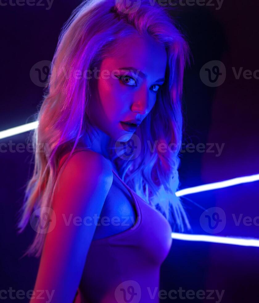 fashion art photo of sexy girl dressed in black in the night-club. Perfect female body with neon lettering on the background