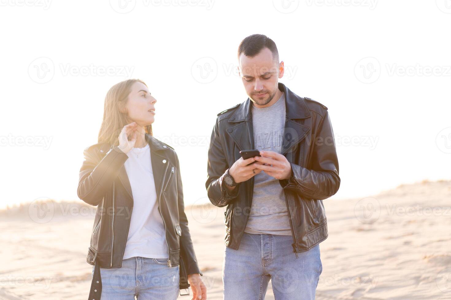 Happy and cute adorable adult couple of millennial hipsters, man with woman girlfriend walking, have fun play, laugh,smile and jump on sunset at desert photo