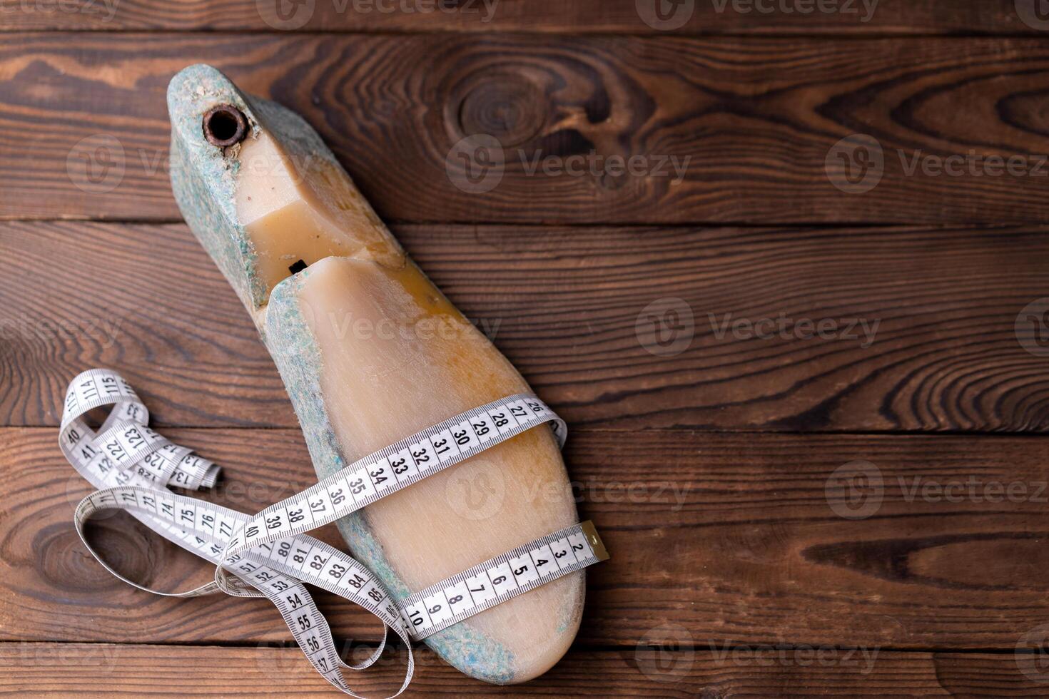 Leather samples for shoes and wooden shoe last on dark wooden table. photo