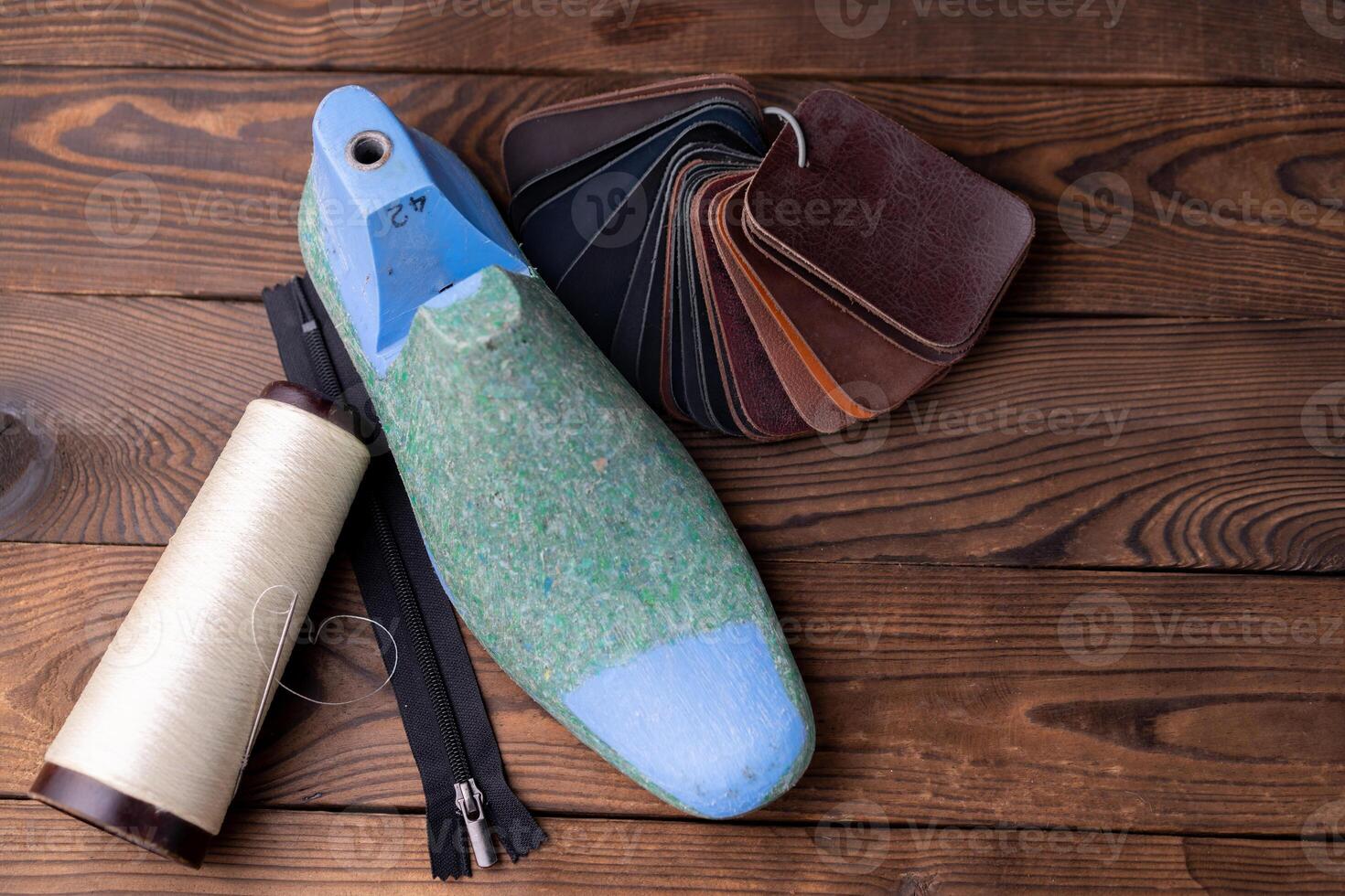 Leather samples for shoes and wooden shoe last on dark wooden table. photo