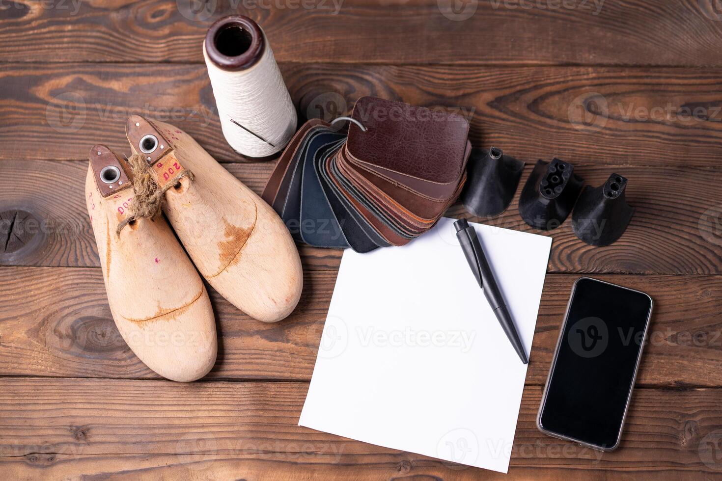 Leather samples for shoes and wooden shoe last on dark wooden table. photo