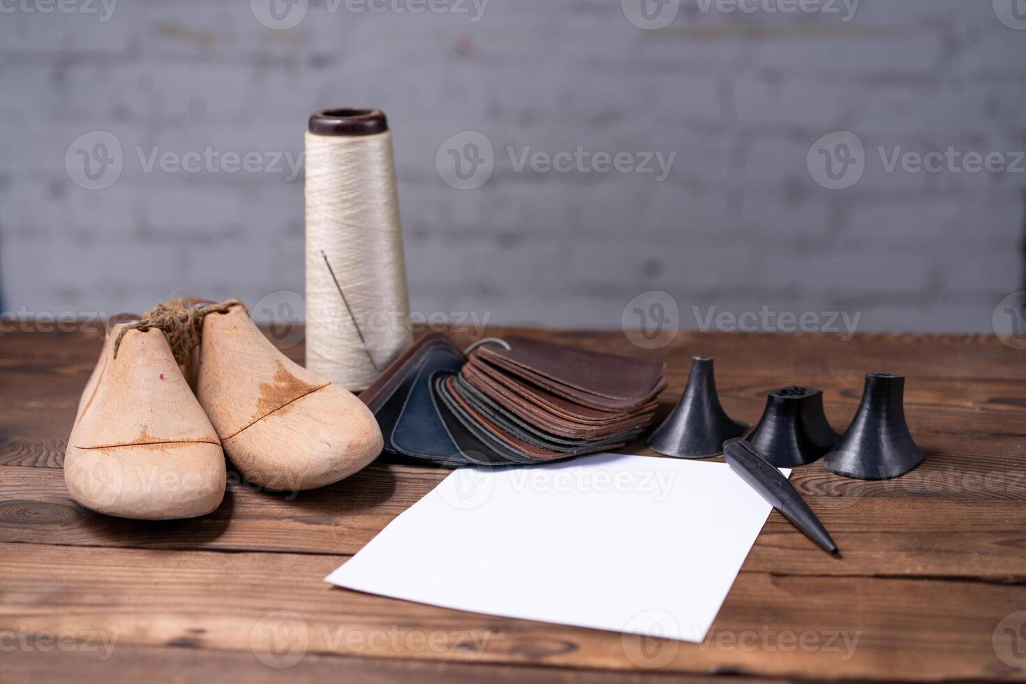 Leather samples for shoes and wooden shoe last on dark wooden table. photo