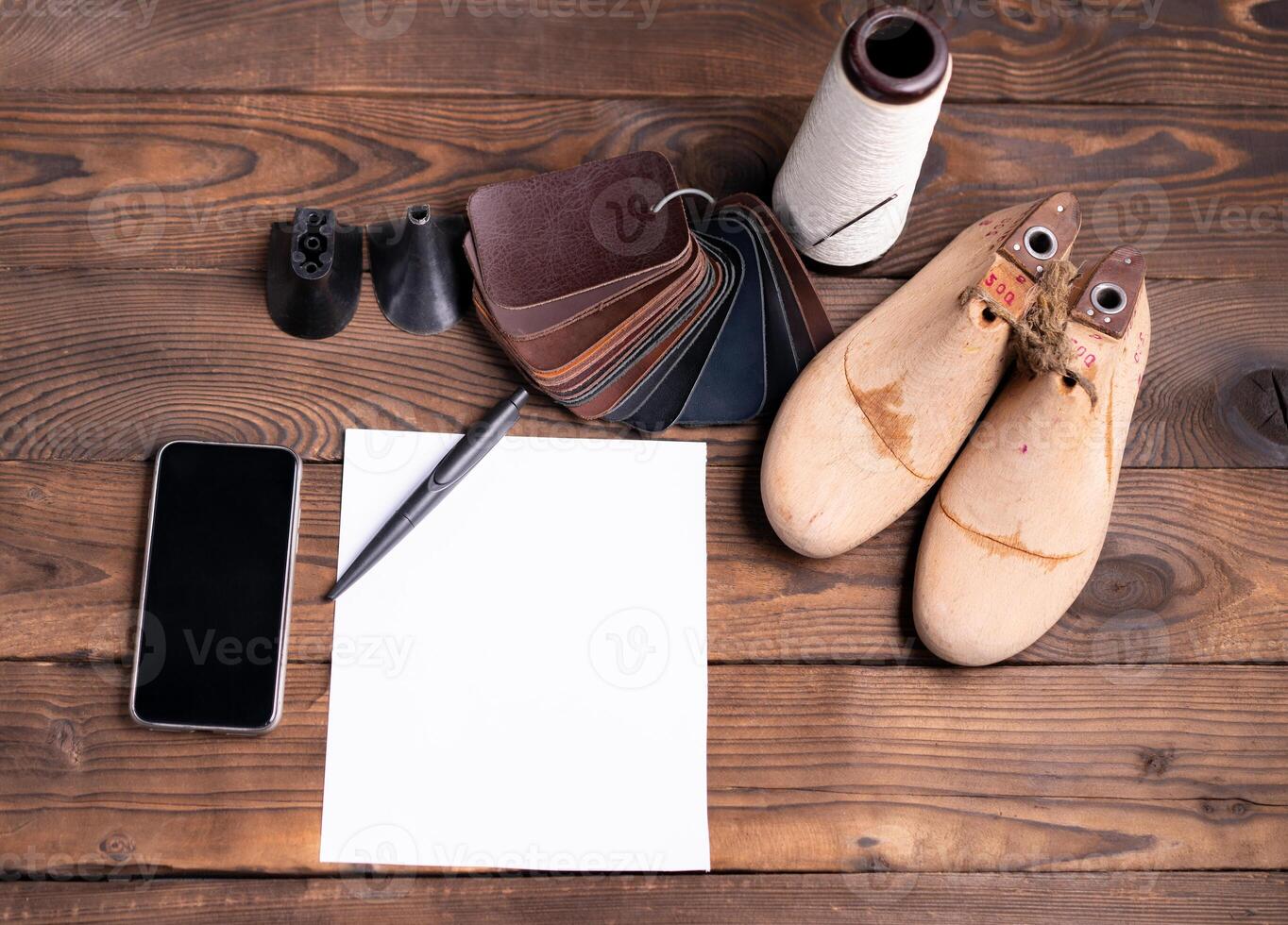 Leather samples for shoes and wooden shoe last on dark wooden table. photo