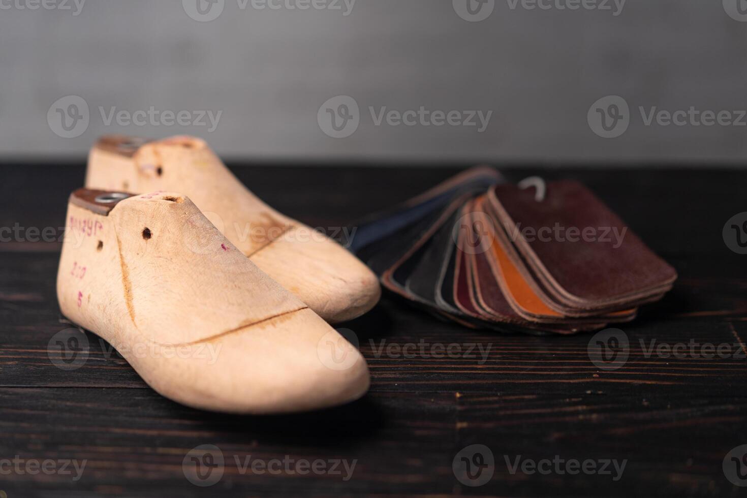 Leather samples for shoes and wooden shoe last on dark wooden table. photo