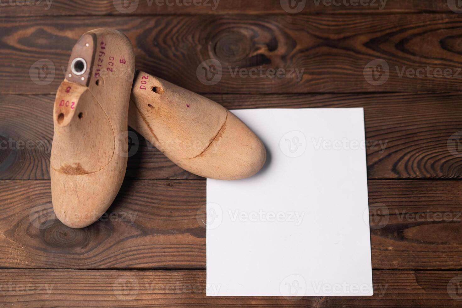 Leather samples for shoes and wooden shoe last on dark wooden table. photo