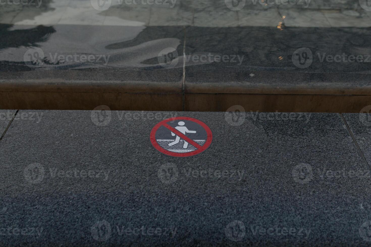 warning sign with pictogram, no swimming or wading. Water in the background. City fountain photo