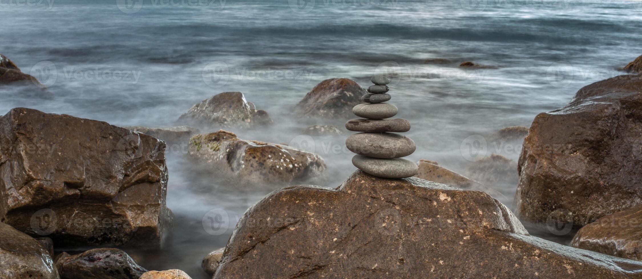 pyramid of stones on a background sea of large stones and water photo