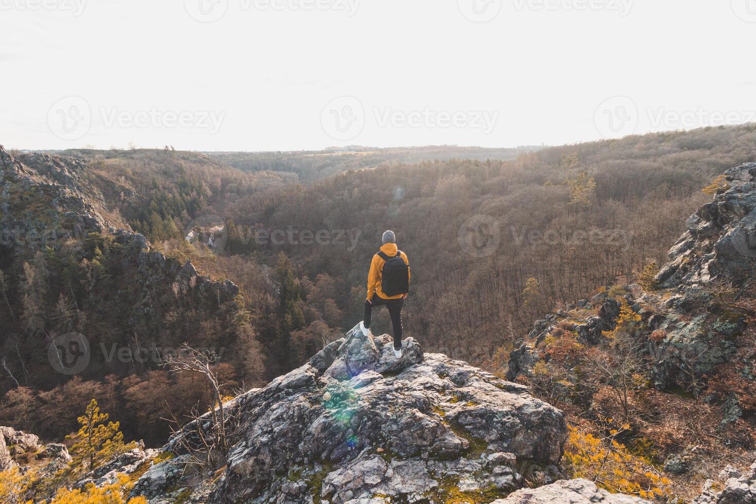 Traveller in a yellow jacket standing on the edge of a rock enjoying a moment of relaxation and a view of the Divoke sarky valley, Prague, Czech Republic. Achieving success photo