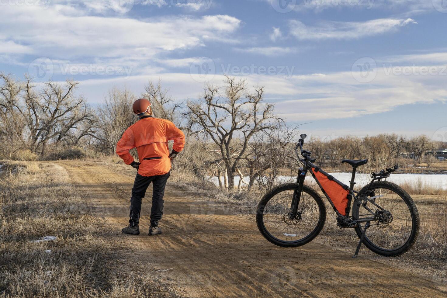 male cyclist with a mountain bike on a dirt trail, winter biking in Loveland, Colorado photo