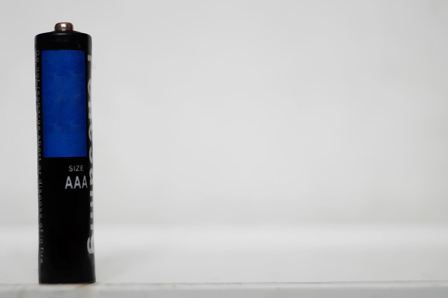 Single AAA-Size Battery Standing Upright on a White Surface photo