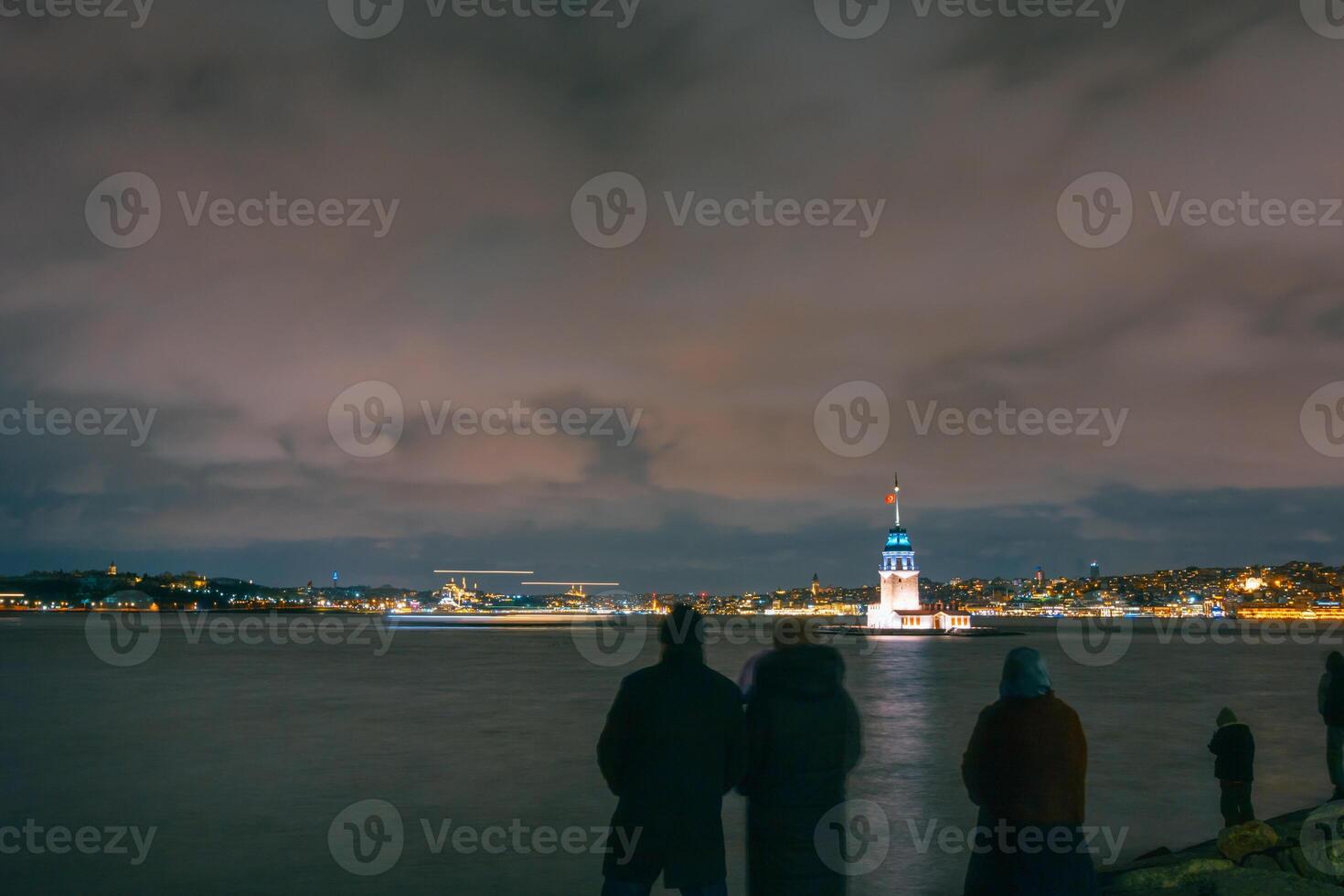 Kiz Kulesi or Maiden's Tower at night with silhouette of people. photo