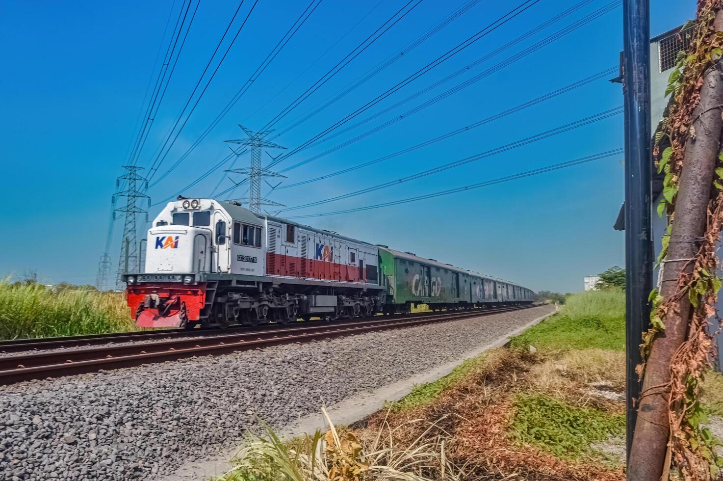 a series of cargo trains with green carriages pulled by a CC201 locomotive made by General Electric belonging to the Indonesian Railway Company, Indonesia, 28 October 2023. photo