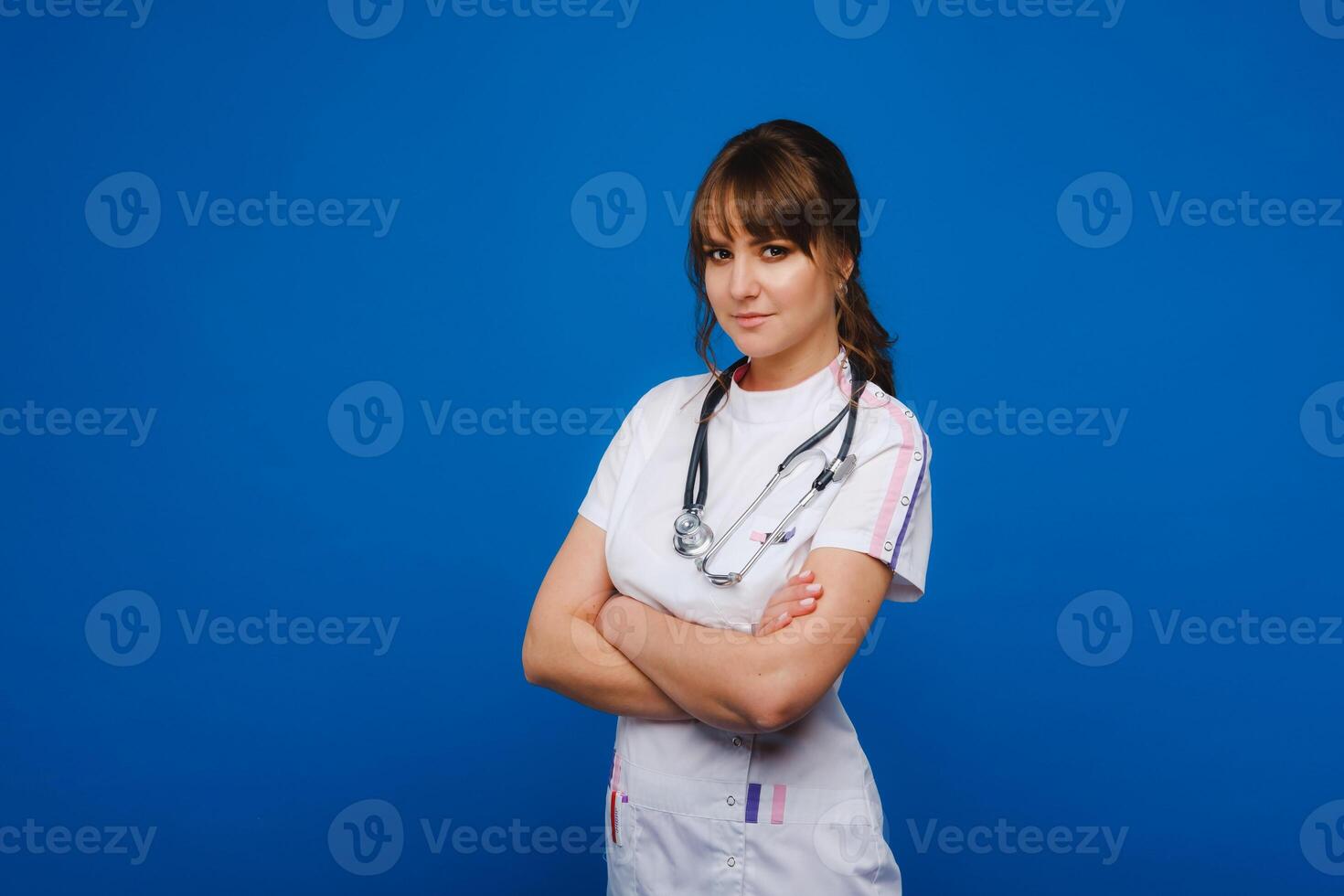 A female doctor, gesticulating, checks the heartbeat in the doctor's office at the hospital with a stethoscope isolated on a blue background photo