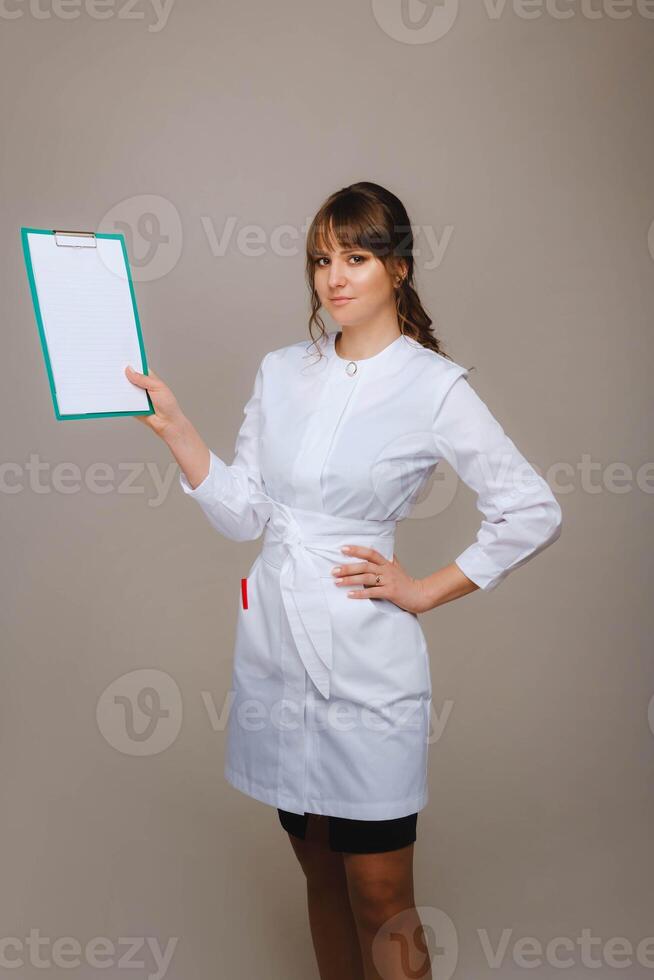 retrato de un hembra médico trabajador en un gris antecedentes con un médico informe.chica médico con un bloc foto