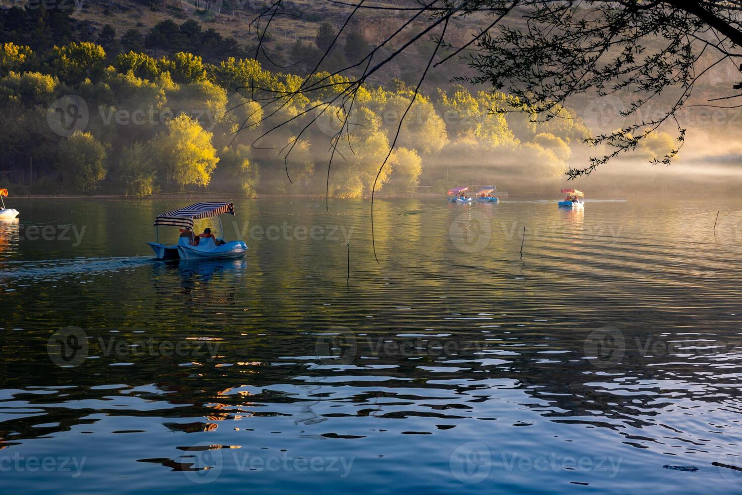 Paddleboats or pedal boats on the lake at sunset with haze or mist photo