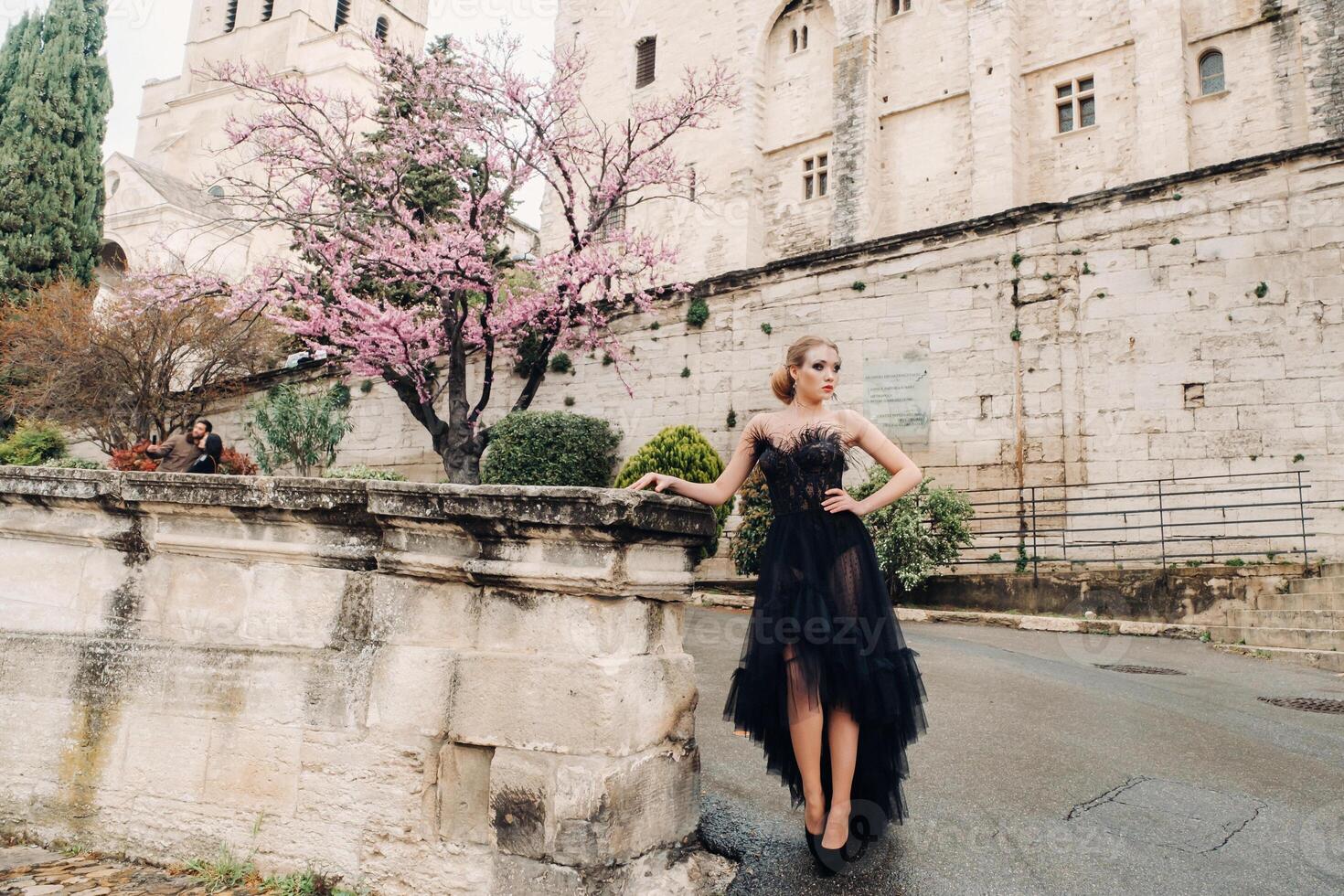 A stylish bride in a black wedding dress poses in the ancient French city of Avignon. Model in a beautiful black dress. Photo shoot in Provence.