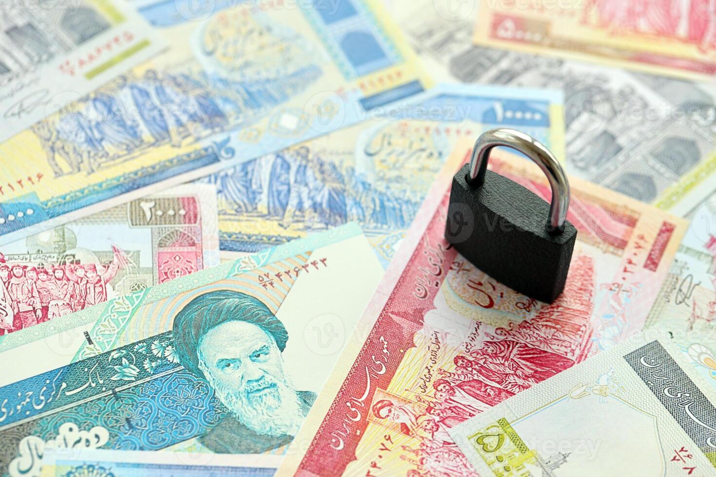 Small padlock lies on pile of iranian money. Sanctions, ban or embargo concept photo