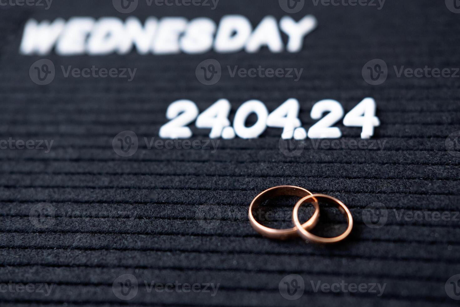 Rings of the newlyweds on the background of a Beautiful date for the wedding 04.24.2024 on a black lettobord photo