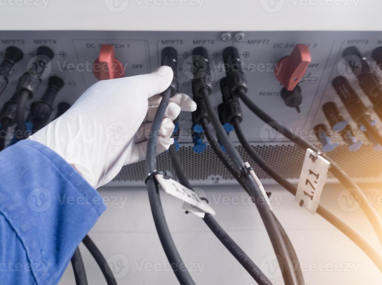 A engineering checking string cable lines in inverter solar panel.The Hand hold a string cable for check and repair. Inverter service concept for technology  background. photo