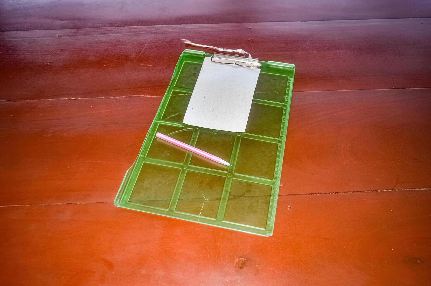 a green plastic clerk's board with a piece of paper stapled to it and a pink pen photo