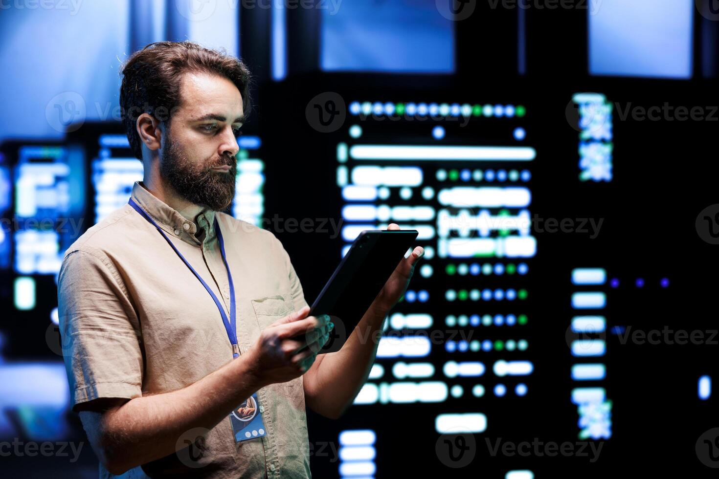 Worker doing system overhaul, imputing data on tablet of required patching in server cabinets. Facility housing advanced data storage equipment supporting critical IT workloads photo