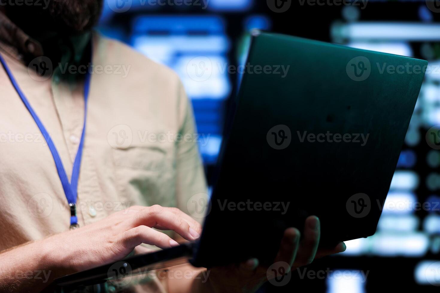 IT specialist using laptop for checkup in data center with advanced data storage servers supporting critical workloads requiring IT equipment to run at high power densities, close up photo