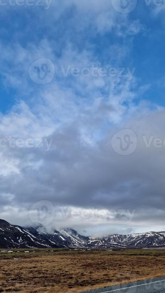 Majestic long road scenery in arctic countryside with fields and snowy hilltops, icelandic natural landscape. Fantastic highway lonely road concept in nordic setting, scenic route. photo