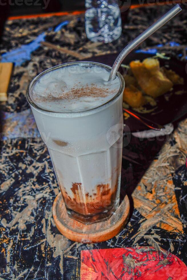 A close-up view of an iced coffee latte on a textured wooden table. photo