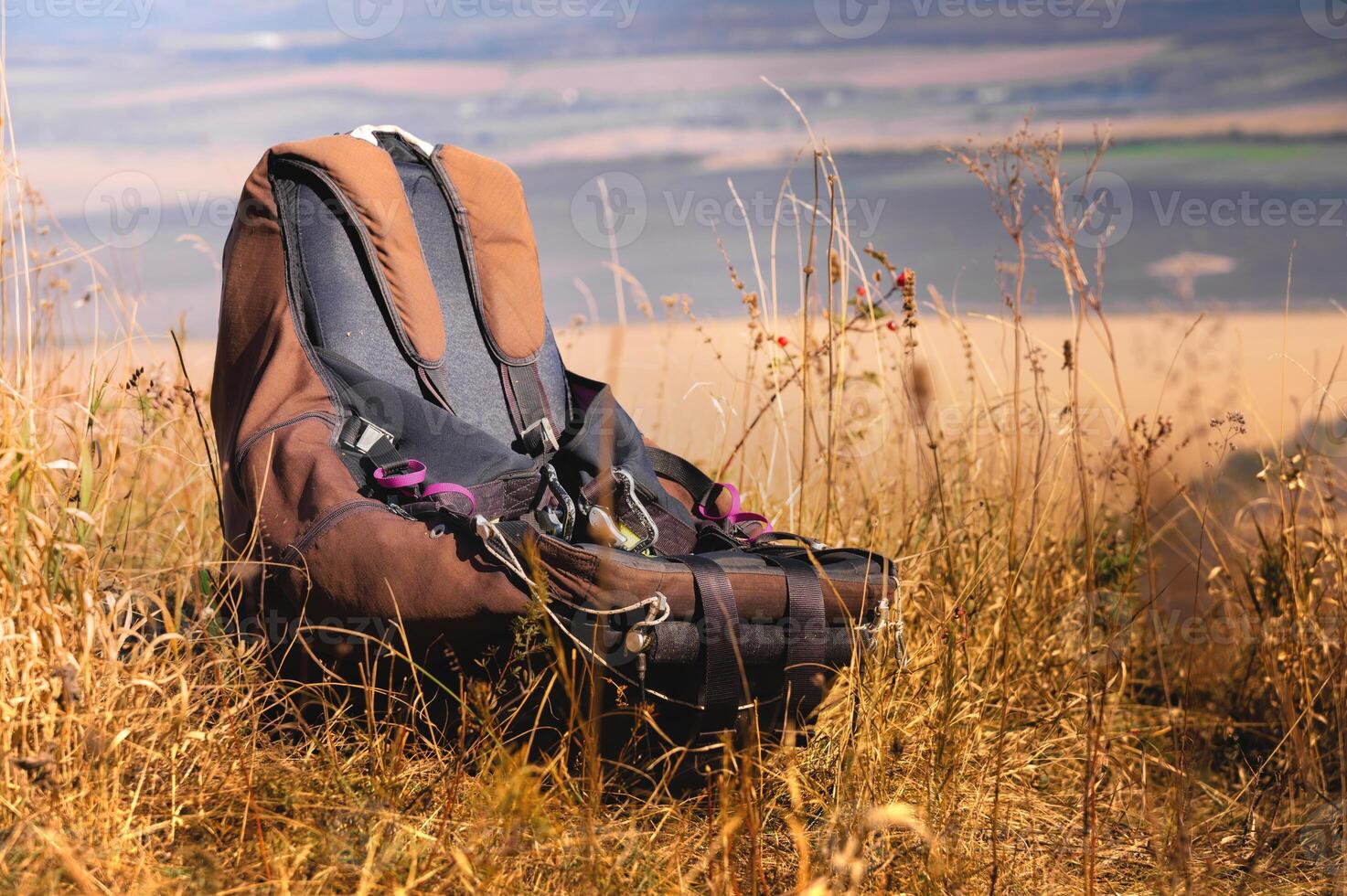The paraglider's harness lies on the grass in the mountains against the backdrop of fields and hills. Paragliding training concept. Nobody photo