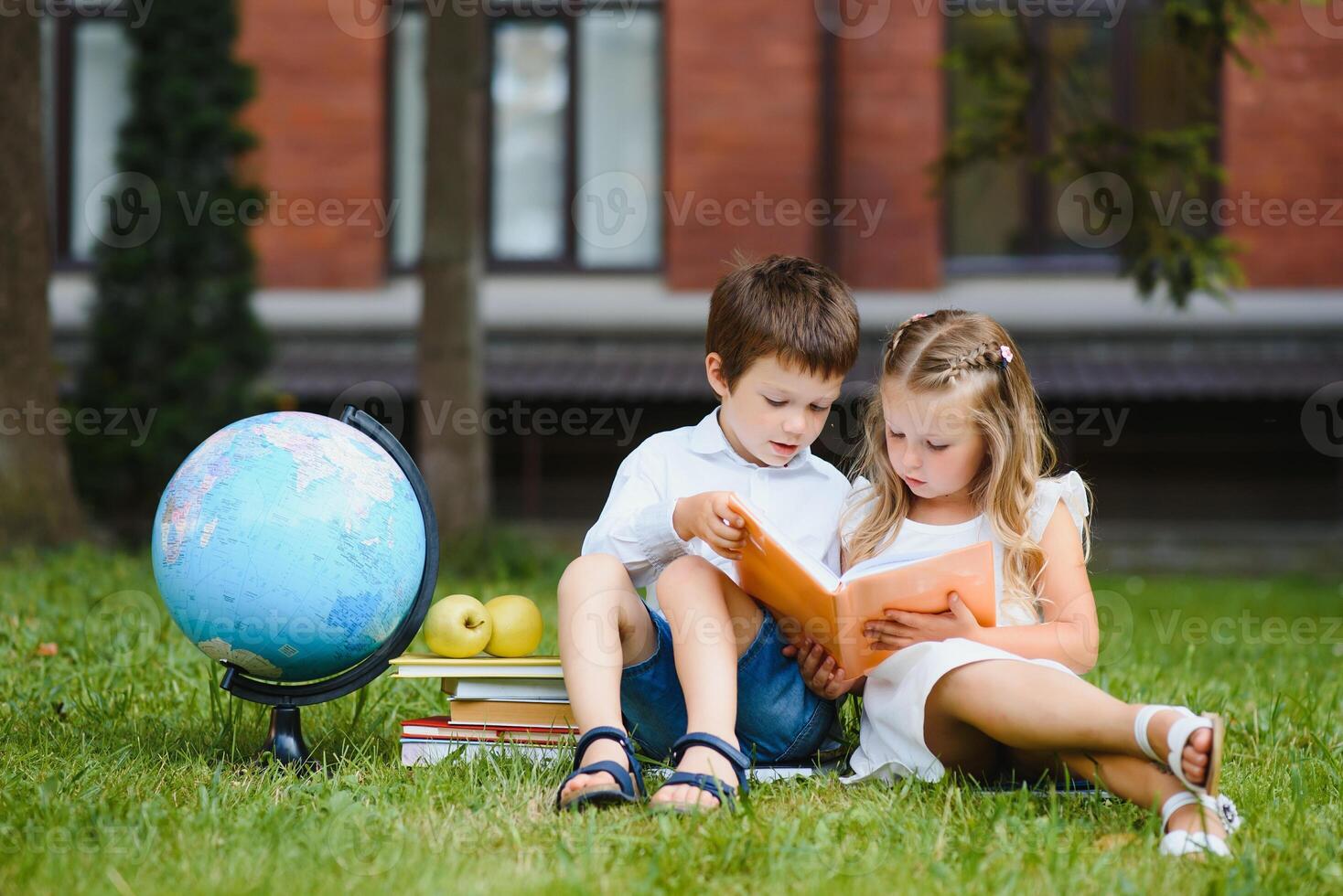 Two pupils of primary school. Boy and girl with school bags behind the back. Beginning of school lessons. Warm day of fall. Back to school. Little first graders. photo