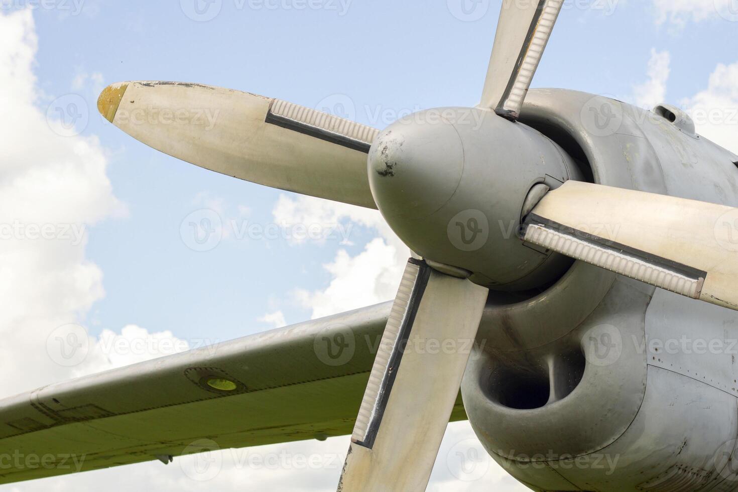 A fragment of airplane wing with four-bladed aircraft propeller against blue sky photo