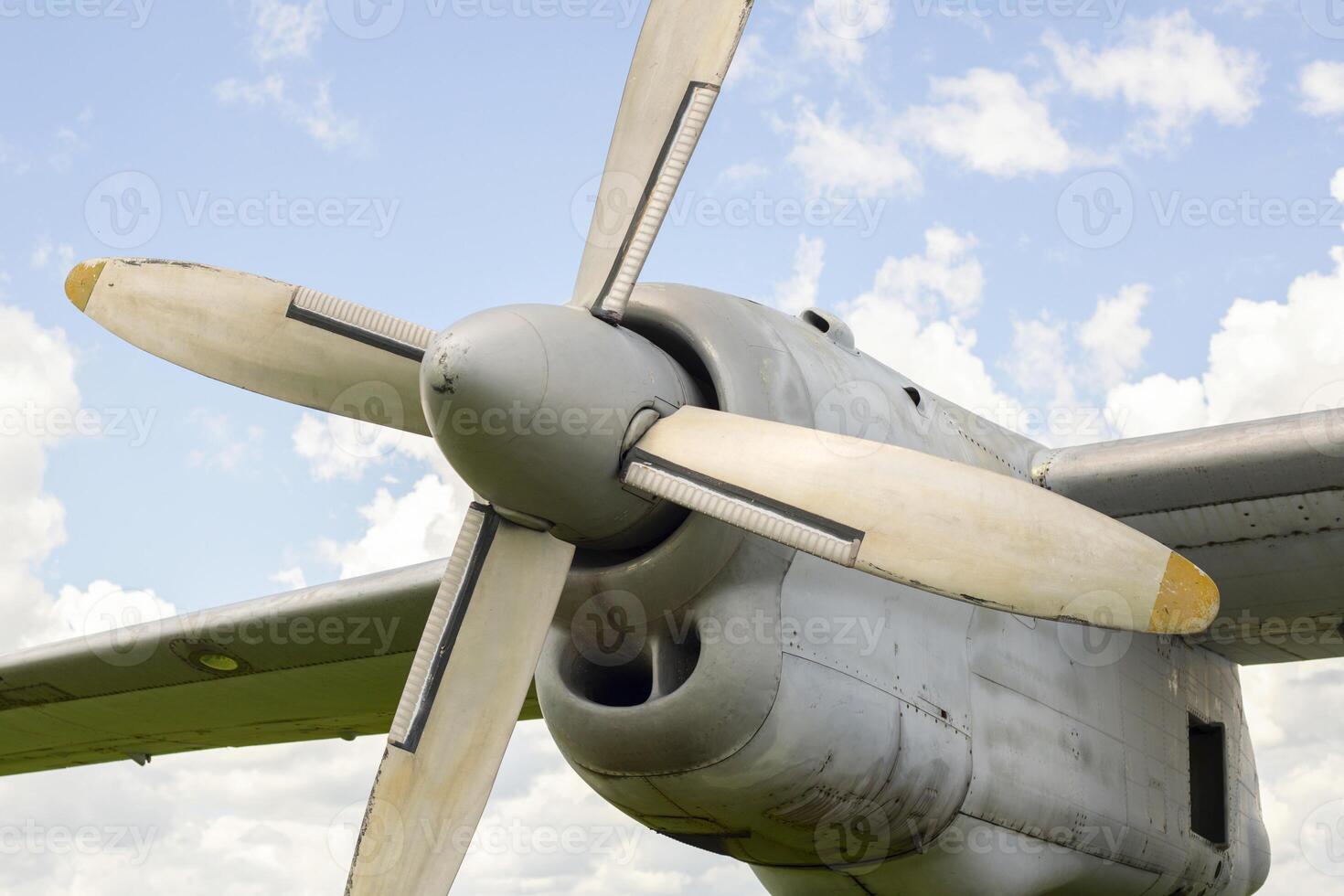 A fragment of airplane wing with four-bladed aircraft propeller against blue sky photo