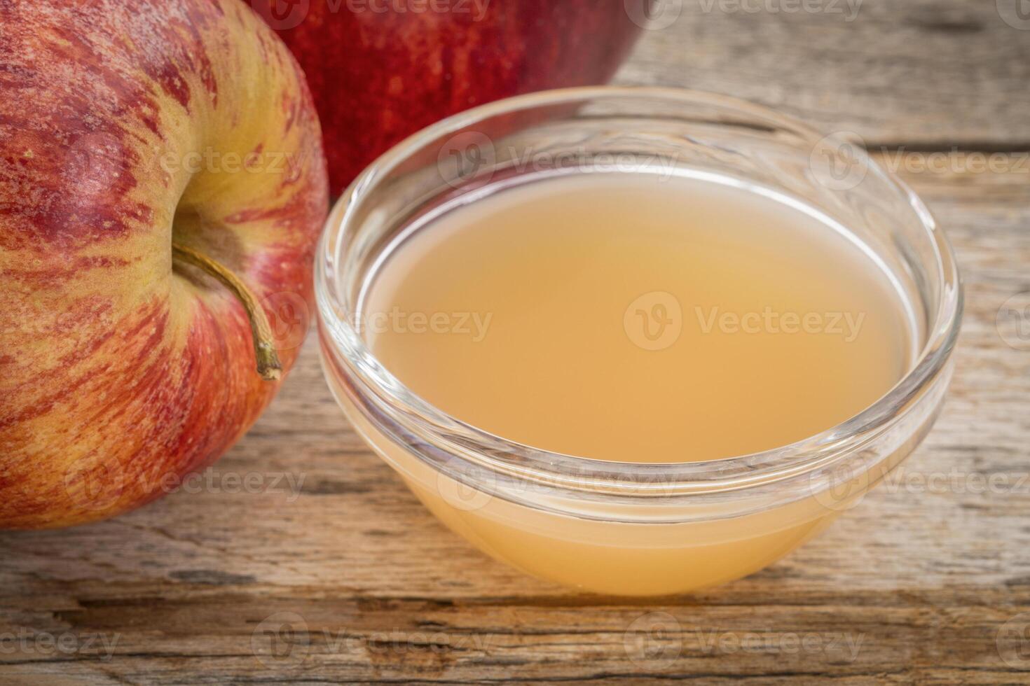 sin filtrar, crudo manzana sidra vinagre con madre - un pequeño vaso cuenco con Fresco rojo manzanas foto