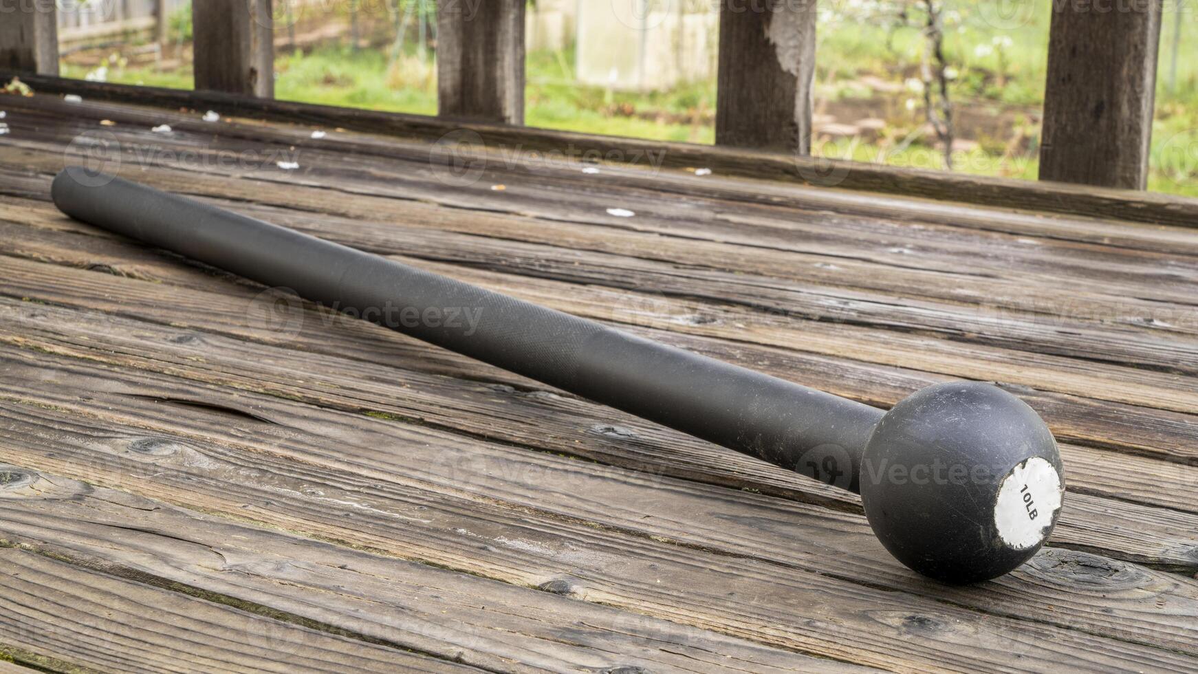 steel mace or macebell on a wooden deck, fitness concept using unconventional equipment, springtime scenery photo