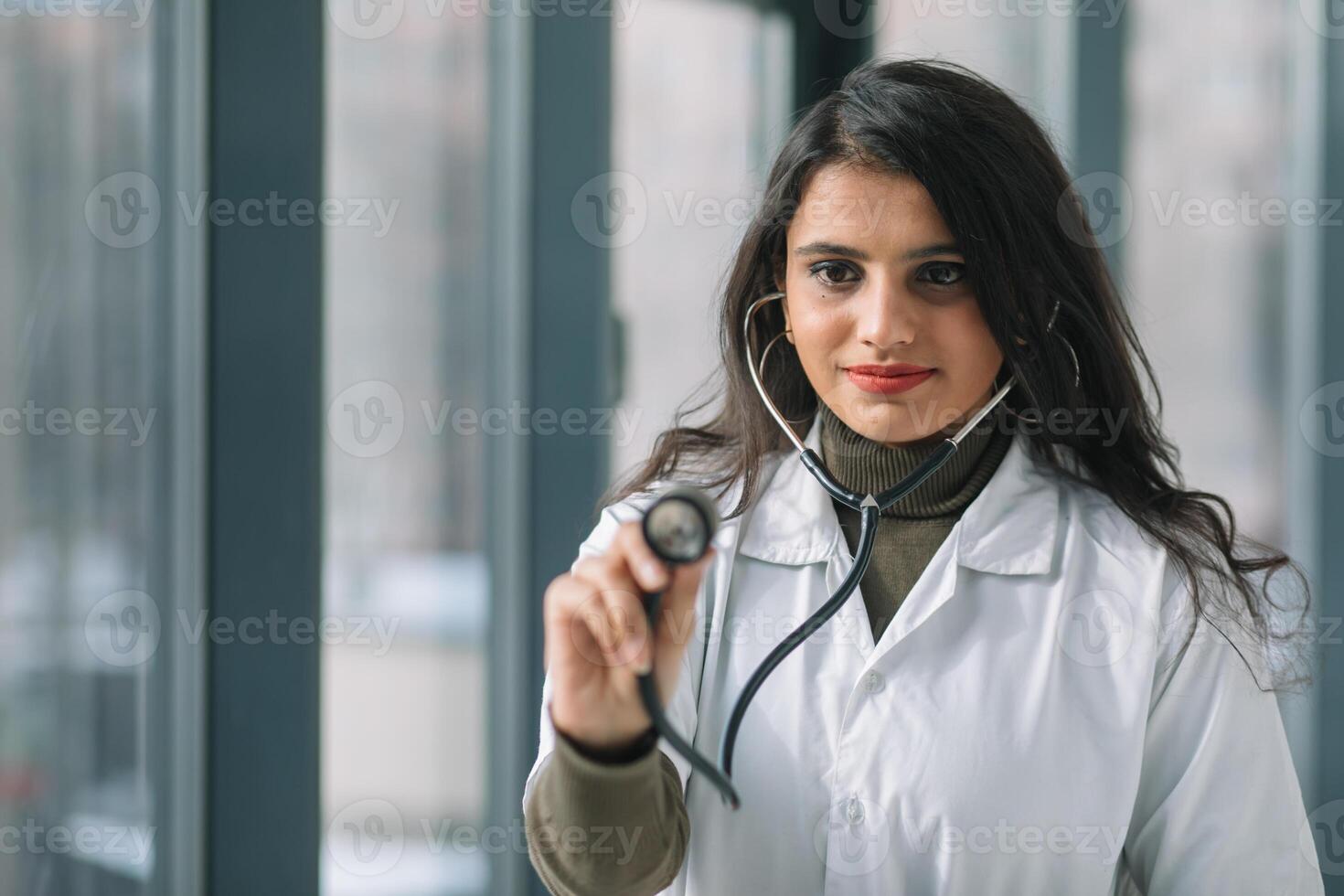 Young Indian medical student at the clinic in practice using a stetoskope in front of camera photo
