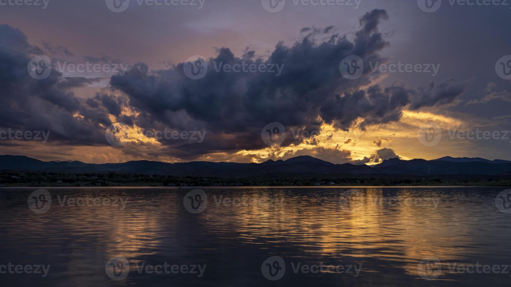 dramatic sunset sky and  clouds over Rocky Mountains and lake in northern Colorado photo