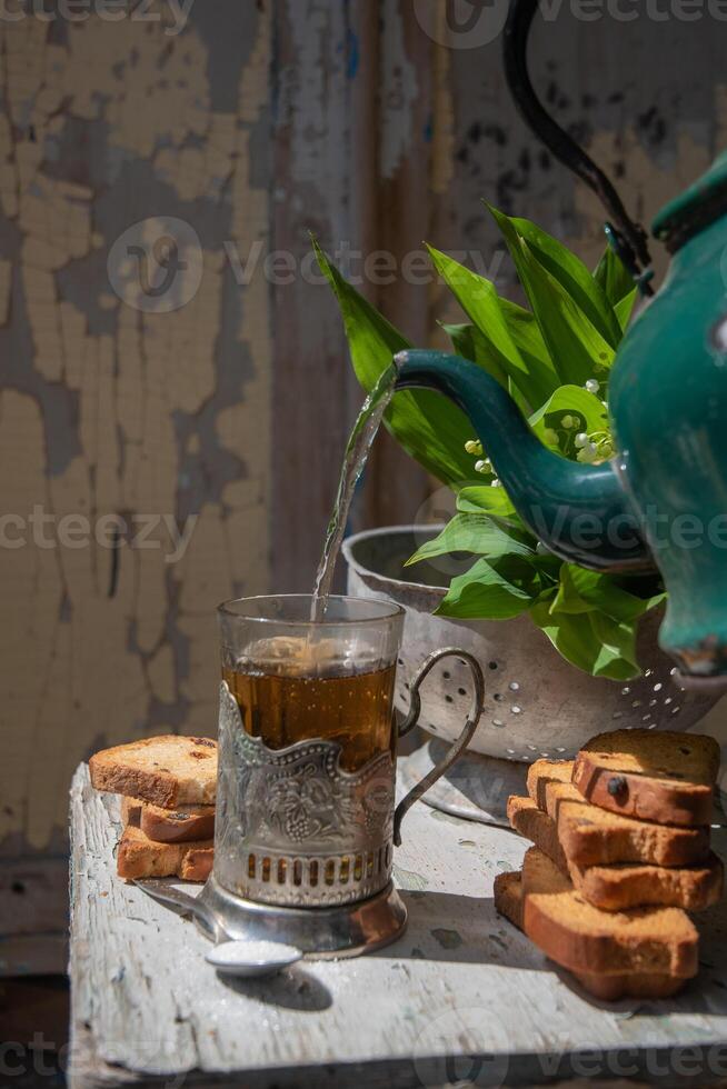 Still life with breakfast,hot tea with sweet raisin crackers for snack,housewife pours drink from enamel green teapot photo