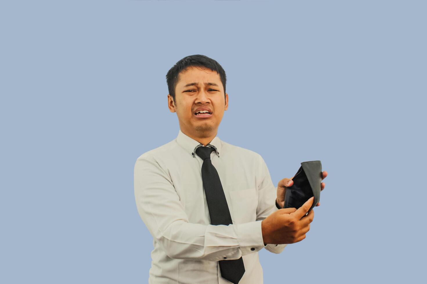 Adult Asian man showing his empty wallet with worried and sad expression photo