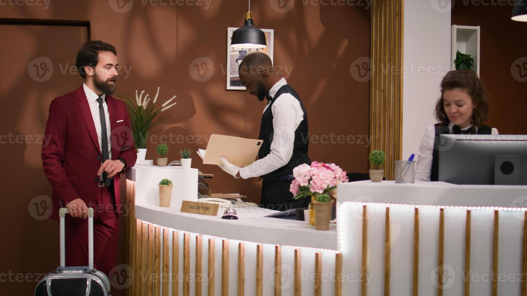 White collar worker asks for hotel services, talking to hotel staff members about leisre activities while he travels on business trip. Professional in suit arriving at reception for check in. photo