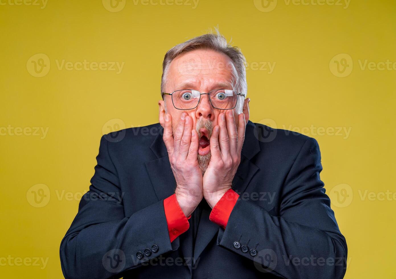 Scared frightened senior man. Frightaned of something. Man covers widely opened mouth with both hands. Displeased surprised expression. Man dressed in suit. Negative emotions. photo