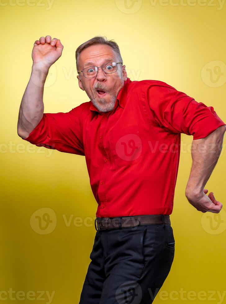 Funny senior man pretending showing the muscles with open mouth. Making funny faces and jestures. photo