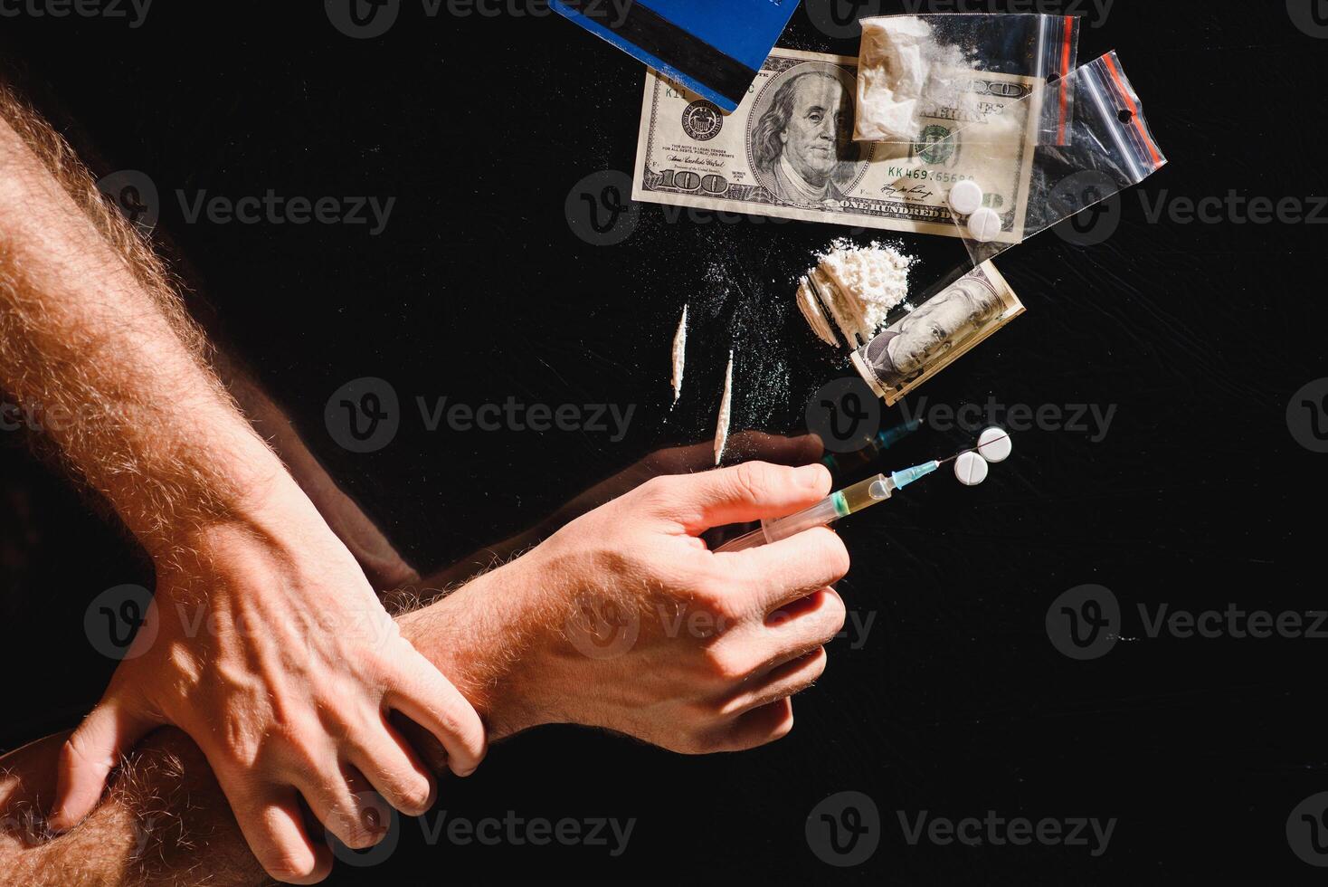 Man's hands trying to abstain from drugs on dark table with cooked heroine, pills, spoon and plastic bag. Concept for drug addiction and International Day against Drug Abuse, top view. photo