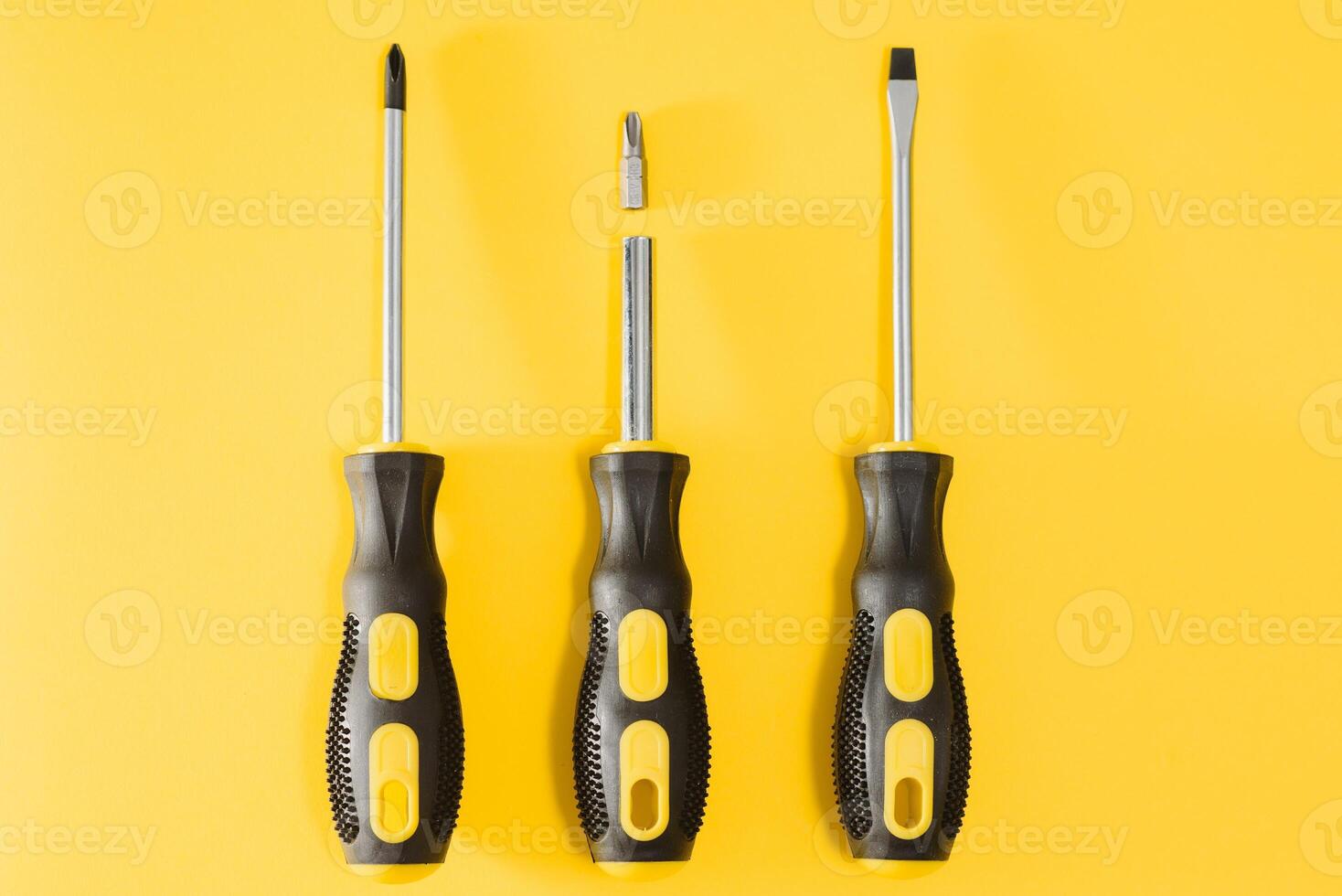 three black and yellow screwdrivers on a yellow background with space for text. Tools, construction and workshop, home repairs, slusar work photo