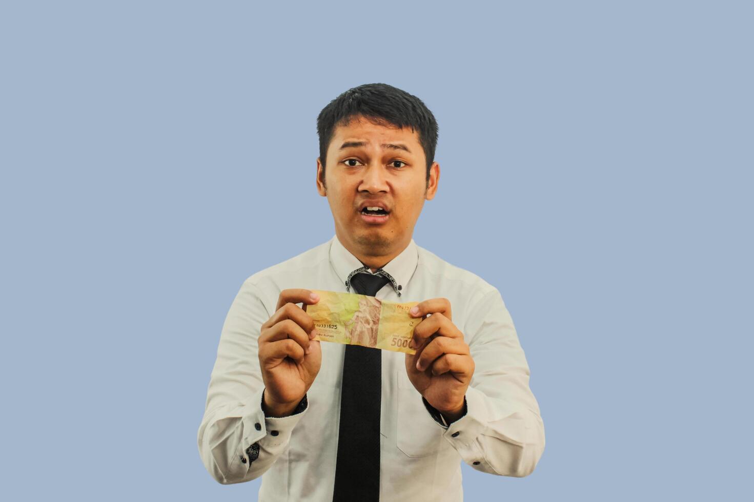 Adult Asian man showing sad expression while holding small amount of money photo