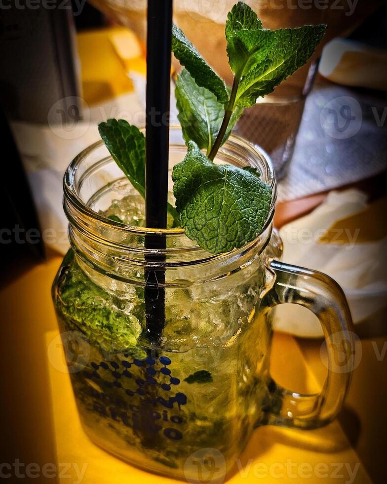 The mojito is a famous cocktail of Cuban origin composed of white rum, lime juice, mint leaves, known as hierba buena in Cuba,  and sparkling mineral water or soda water or seltz water. photo