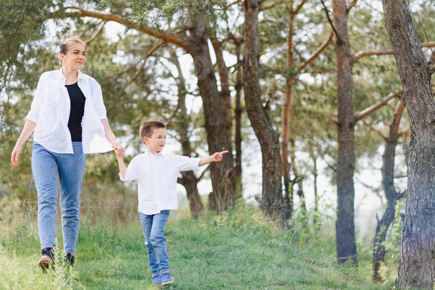 Mother and little son happy family. Attractive mom,kid boy are walking carefree outdoors summer. Parent woman goes on nature together with child,summer,spring day.Light,copy space. Happy family. photo